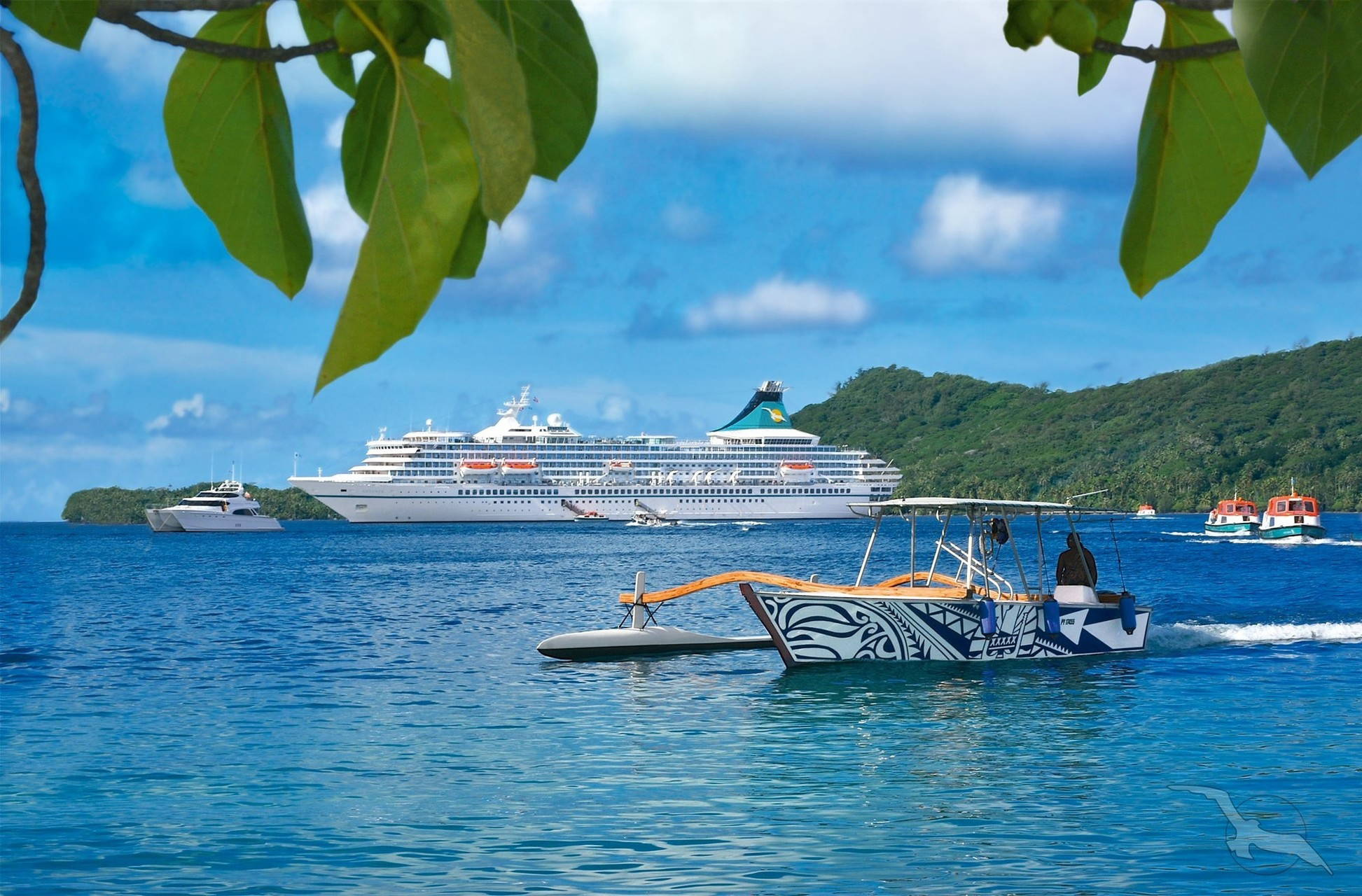 Die MS Artania vor tropischer Kulisse auf dem türkisblauen Meer und einem kleinen Boot im Vordergrund